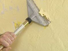 a man holding a paintbrush in his hand and painting the wall with yellow paint