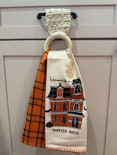 an orange and white towel hanging from a hook on a cabinet door with a house design