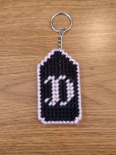 a black and white knitted keychain with the letter d hanging from it