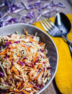 a bowl filled with coleslaw and carrots next to a fork