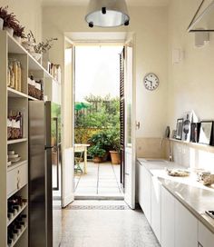 a long narrow kitchen with white cabinets and stainless steel appliances on either side of the door