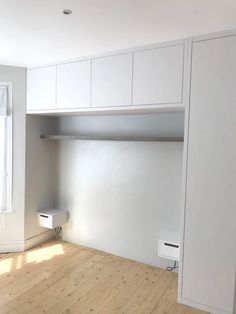 an empty room with white cabinets and wood floors