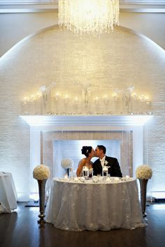 a bride and groom kissing under a chandelier