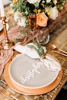 a table set with plates, napkins and flowers on top of each plate is decorated with an inscription