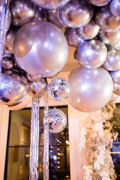 silver and white balloons are hanging from the ceiling