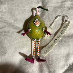 a green figurine with pink shoes and a name tag hanging from it's neck