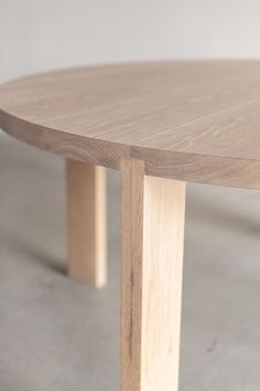 a close up of a wooden table with white walls in the background and concrete flooring