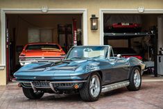 a classic car parked in front of a garage