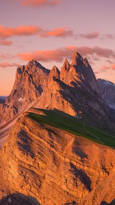 the mountains are covered in green grass and brown rocks, with a road running between them