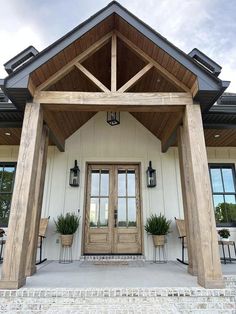 the front entrance to a home with two chairs and potted plants