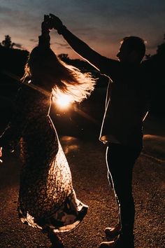 a man and woman dancing in the street at night with their arms around each other