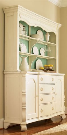 a white china cabinet with dishes on it