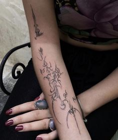 two women with matching tattoos on their arms sitting next to each other and holding onto one another's arm