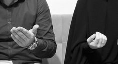 two people sitting on a couch with their hands together