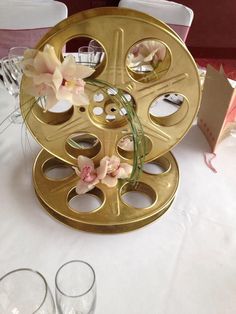 a gold reel with flowers on it sitting on a table next to empty wine glasses