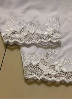 two pieces of white lace sitting on top of a table