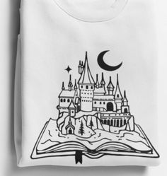 an open book with a castle on it and the moon in the sky above it