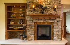 a living room with a stone fireplace and built in bookshelves