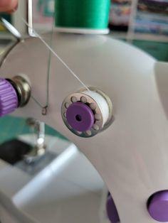 the sewing machine is being worked on by someone using scissors to sew something purple and white