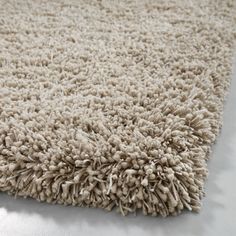 an area rug is shown with white shag on the floor and beige carpeting