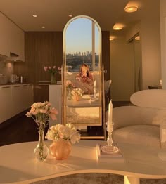 a woman taking a selfie in front of a mirror with flowers and candles on the table