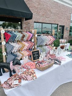 the table is covered with quilts and other items for sale in front of a brick building