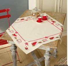 a table with a red cup and two cups on it, sitting next to a chair