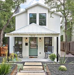 a white house with two rocking chairs on the front porch and steps leading up to it