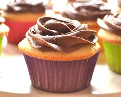 cupcakes with chocolate frosting and sprinkles sitting on a table