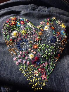 an embroidered heart on the back of someone's jean jacket with flowers in it