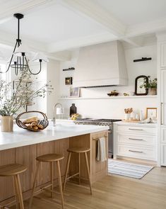 a kitchen with white cabinets and wooden stools in front of an island countertop