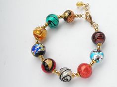 "Alessandro's Custom Designed Bracelet, handmade with round, 14mm genuine Murano glass, Venetian Beads, and one 12mm round beads, with an 8mm round gold bead dangling at the end of the adjustable chain. The bracelet shown in the photos is approximately 8 1/4 inches, adjustable to 9 1/4 inches, with gold filled lobster style, spring clasp and chain. But, you can request a custom order, with another length. Note: larger beads, such as 14mm round, take up more space on your arm. When choosing the l Bracelets Design, Feather Design, Glass Bracelet, Beads Handmade, Style Spring, Bracelet Handmade, Beaded Dangles, Gorgeous Necklaces, Gold Beads