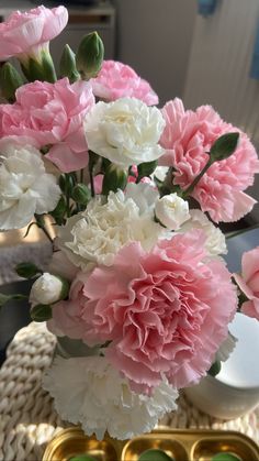 pink and white carnations in a vase on a table next to an egg tray