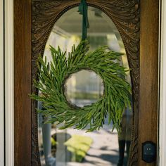 a wooden door with a wreath hanging from it's side frame and a mirror behind it