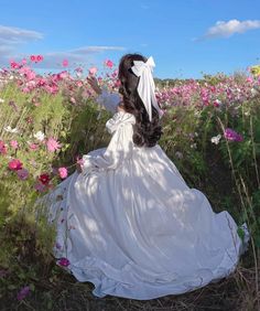 a woman in a white dress sitting in a field of flowers