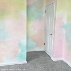 an empty room with pastel paint on the walls and carpeted floor in front of a door