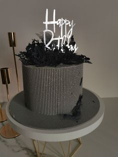 a black and silver birthday cake with white frosting on it's top sitting on a table