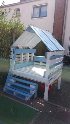 a house made out of pallets sitting on the side of a road in front of a building