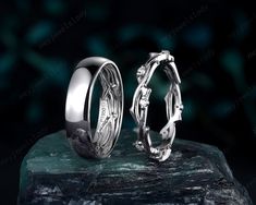 two wedding rings sitting next to each other on top of a green stone slab in front of a black background