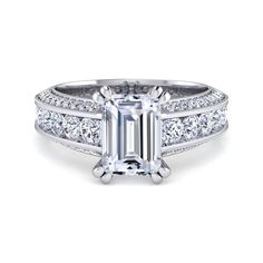 an emerald cut diamond engagement ring with side stones on the shoulders and sides, set in white