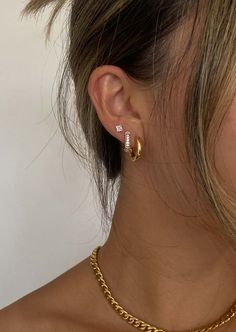 a woman wearing a gold chain necklace and matching earring with a pair of earrings