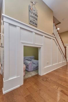 a dog bed in the entry way of a house with stairs and carpet on the floor