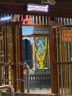 an entrance to a temple with a statue in the doorway and metal bars around it