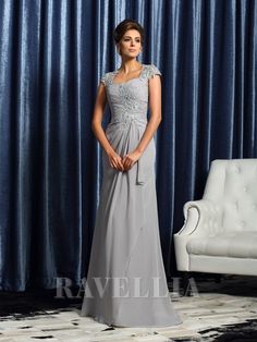 a woman standing in front of a blue curtain wearing a gray dress with beading