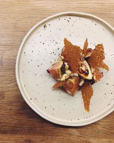 a white plate topped with fruit and nuts on top of a wooden table covered in dirt