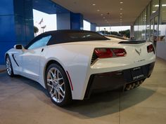 a white sports car is parked in a showroom