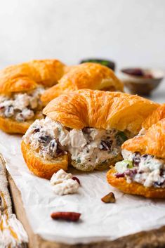 croissants filled with chicken salad sitting on top of a cutting board