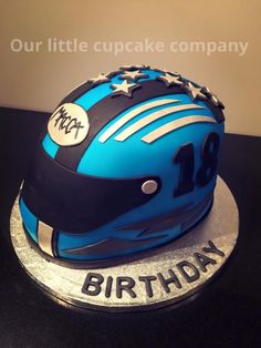 a blue motorcycle helmet cake on top of a black table with the words happy birthday written on it