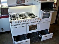 a white stove top oven sitting inside of a kitchen next to two bins on the floor