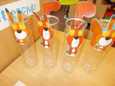 three plastic cups with cartoon animals on them sitting on a table in front of a sign